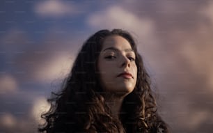 Une femme aux cheveux longs debout devant un ciel nuageux