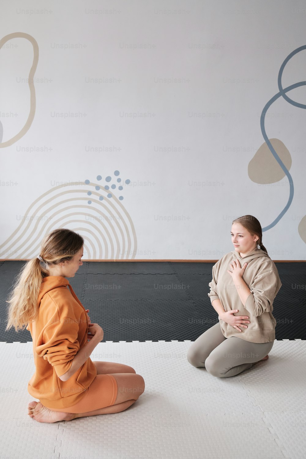 a woman sitting on a mat talking to another woman