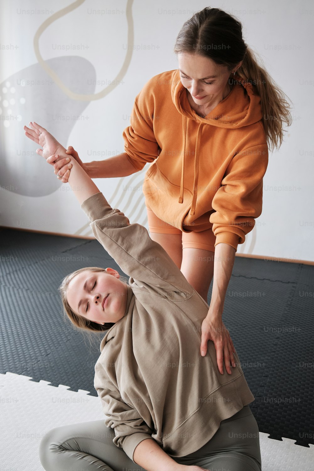 Eine Frau hilft einem jungen Mädchen auf dem Boden