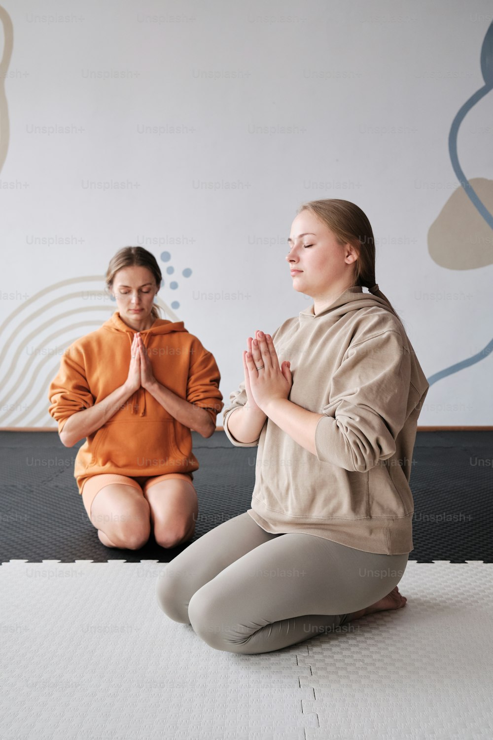 two women sitting on a mat in a yoga pose