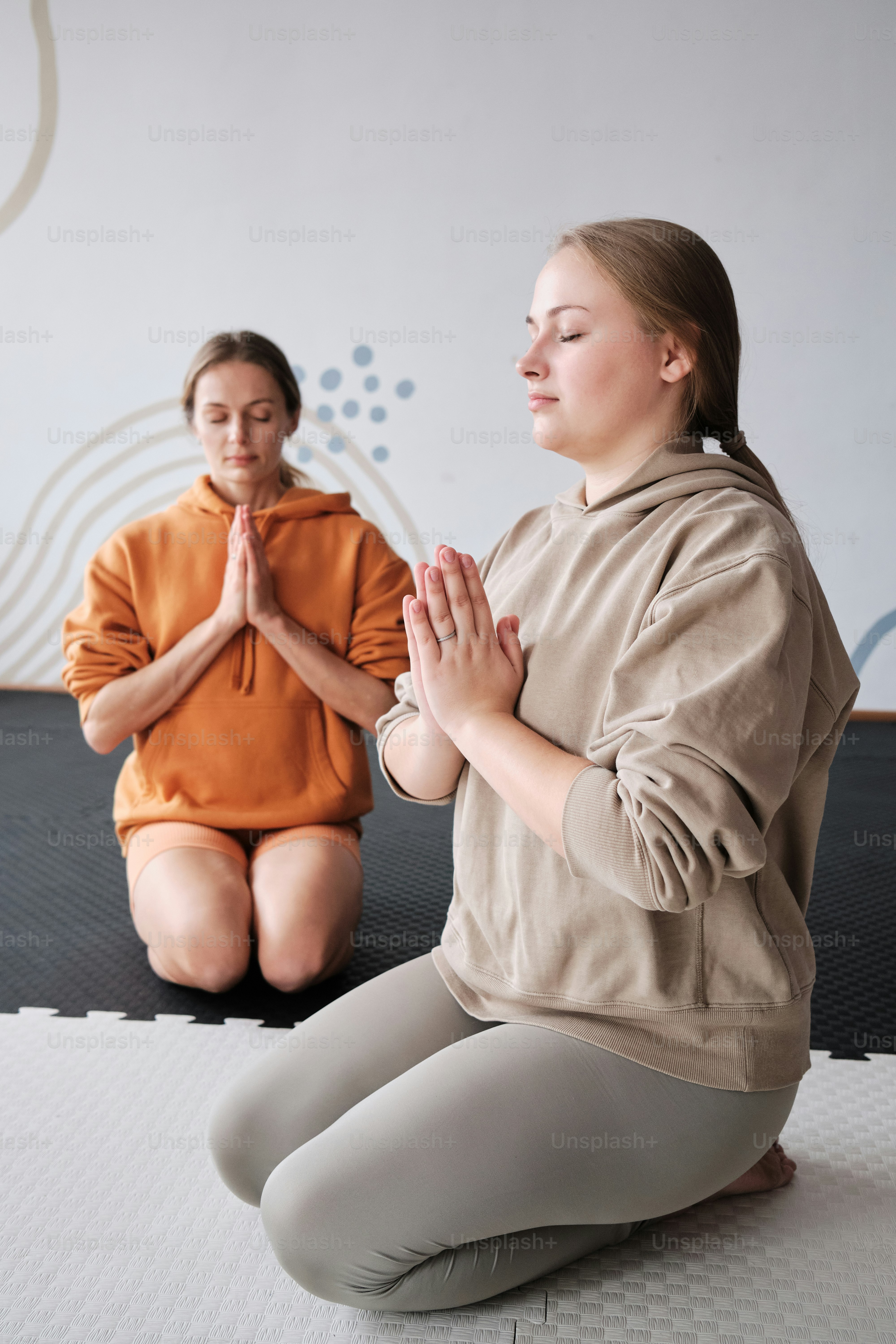 Una mujer sentada en una colchoneta frente a otra mujer