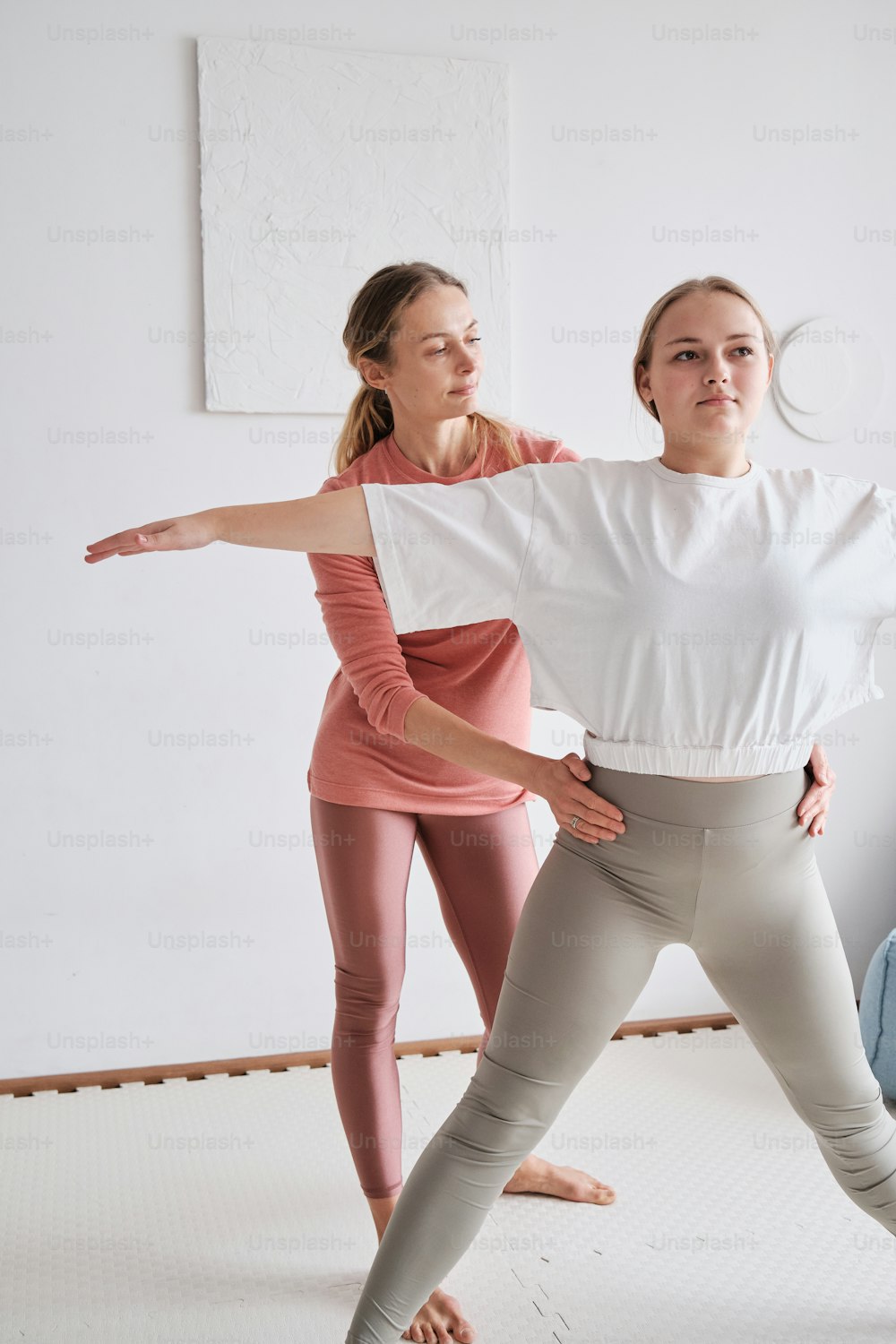 two women are doing yoga poses in a studio