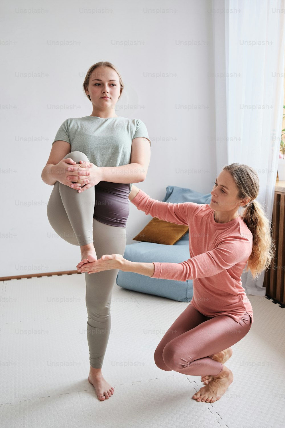 two women doing yoga poses in a living room
