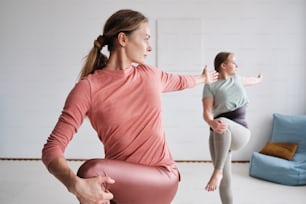 two women doing yoga in a white room