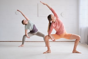 Ein paar Frauen stehen auf einem Bein in einer Yoga-Pose