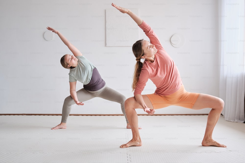 a couple of women standing on one leg in a yoga pose