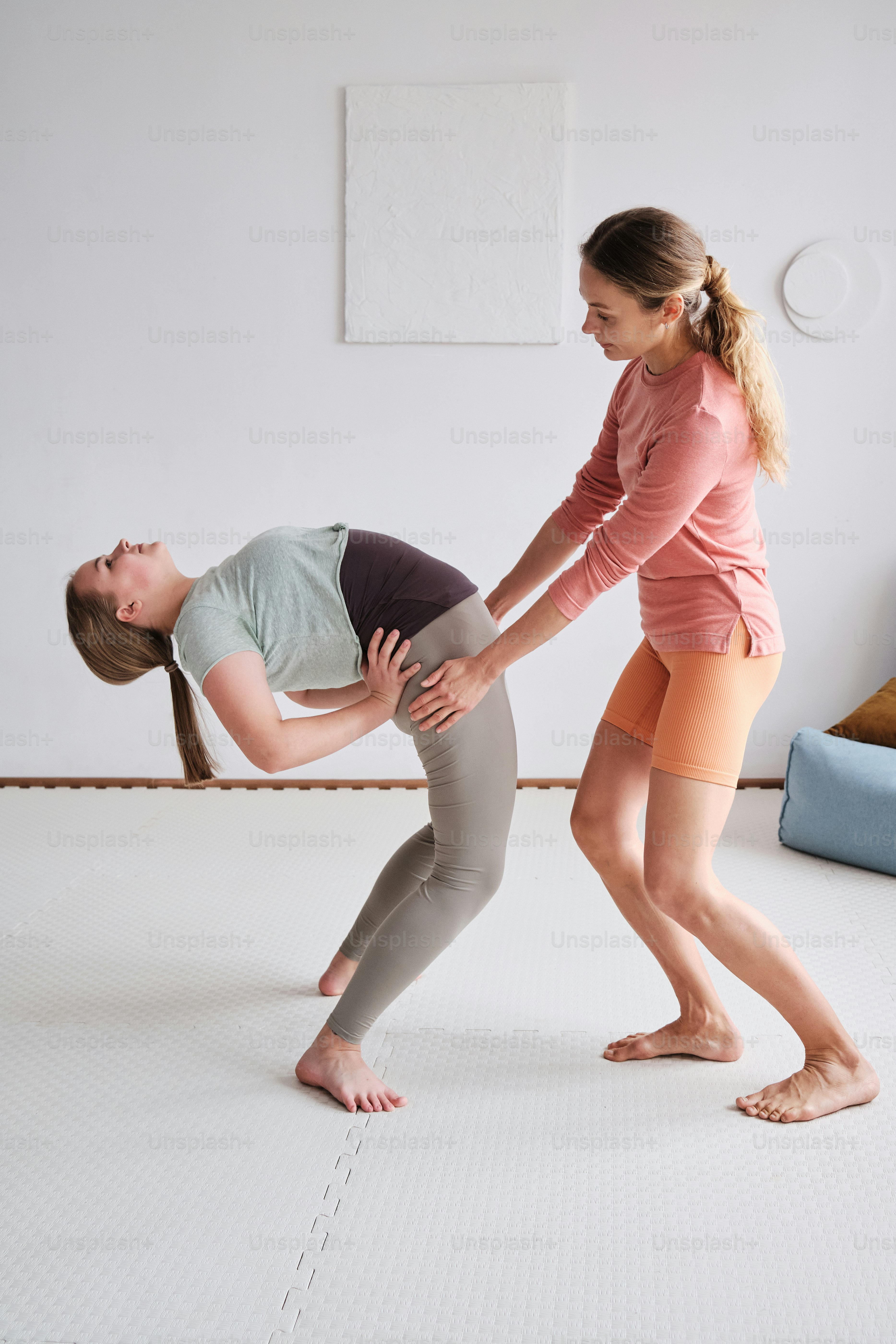 Una mujer ayudando a otra mujer con una postura de yoga
