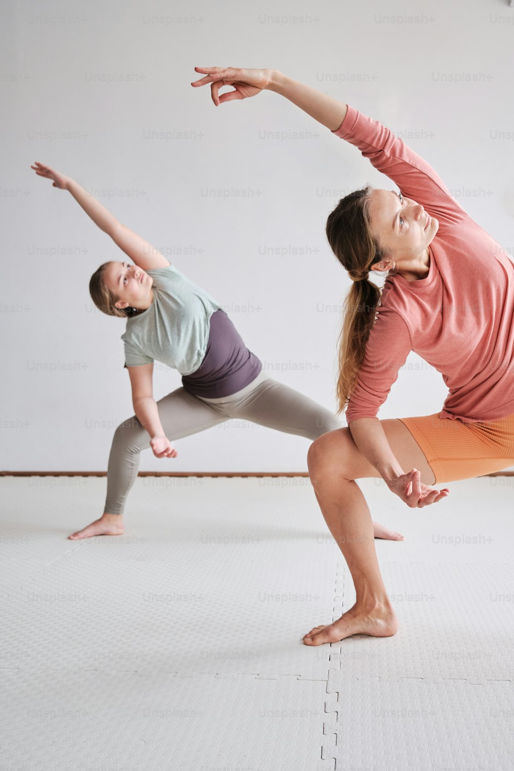 uma mulher e uma criança fazendo uma pose de yoga