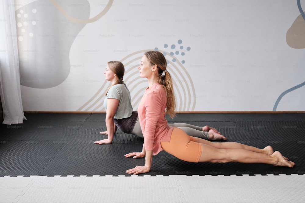 um casal de mulheres sentadas em cima de um tapete de yoga