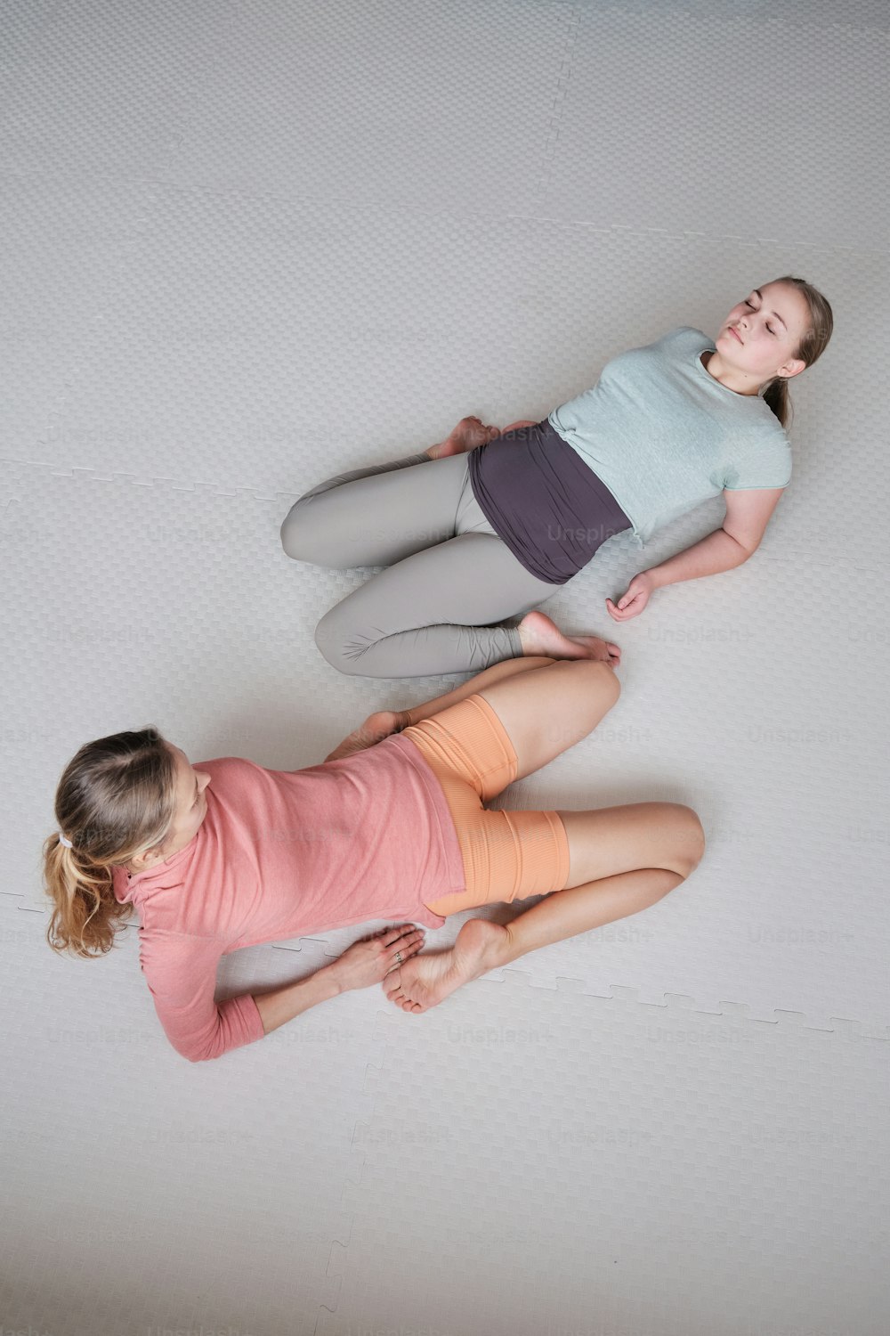 two young girls laying on a mattress together