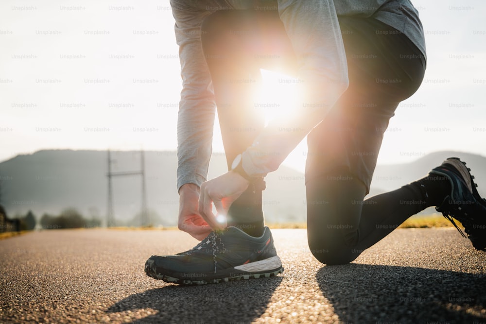 a person tying their shoe laces on a road