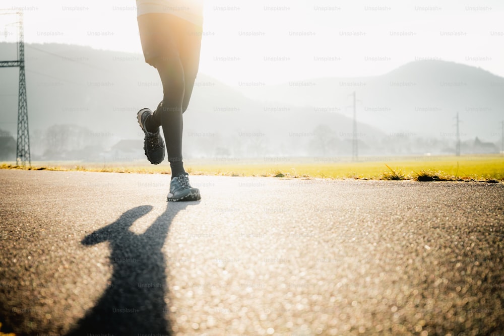 Foto Uma pessoa correndo por uma estrada ao sol – Imagem de