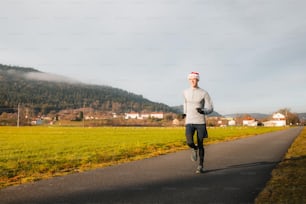 Un uomo in un cappello di Babbo Natale che corre lungo una strada