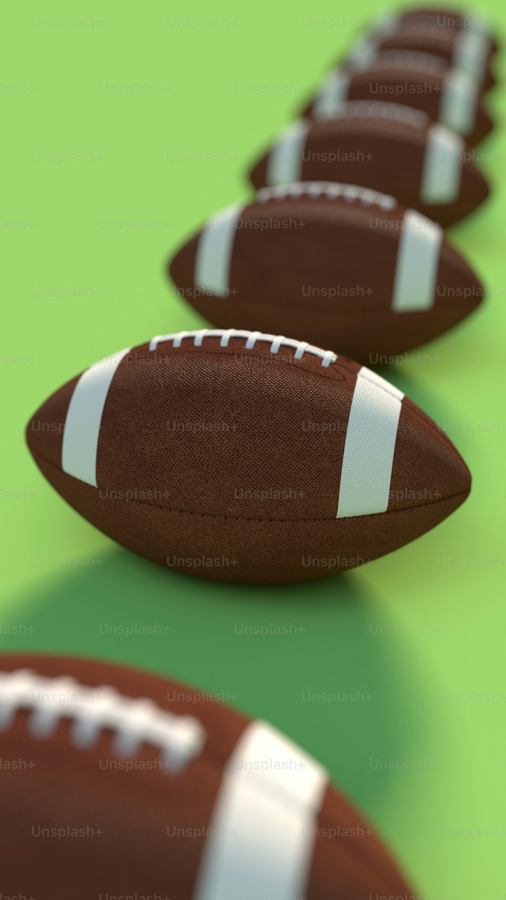a row of footballs sitting on top of a green surface