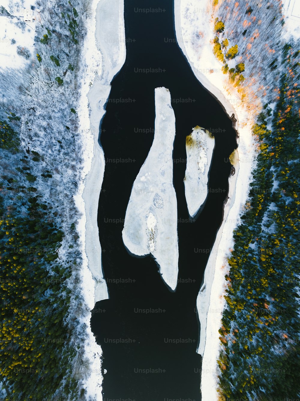 an aerial view of a body of water surrounded by snow