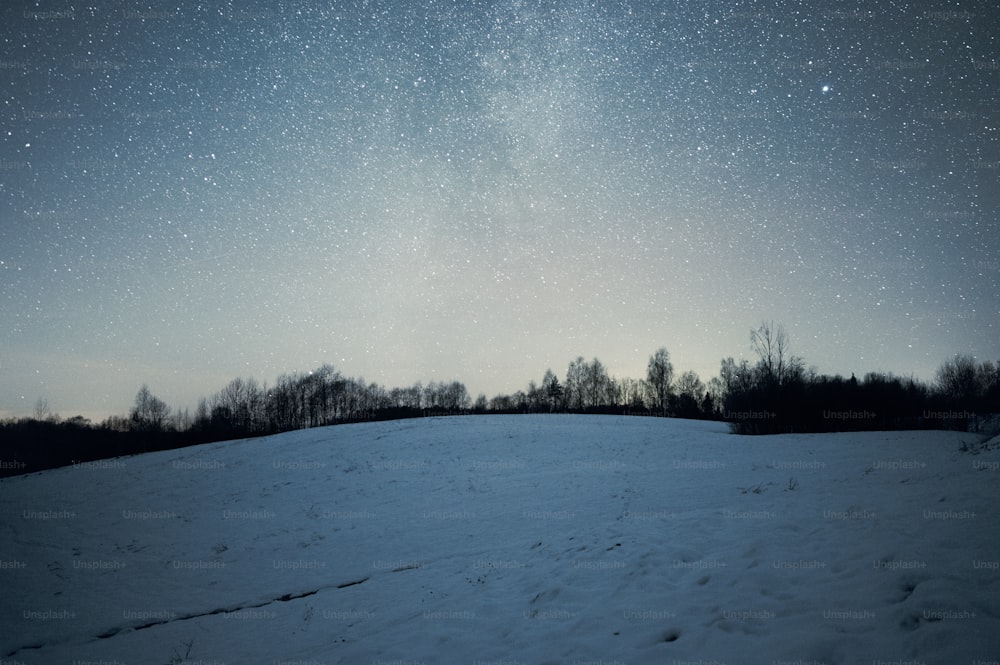 a field covered in snow under a night sky