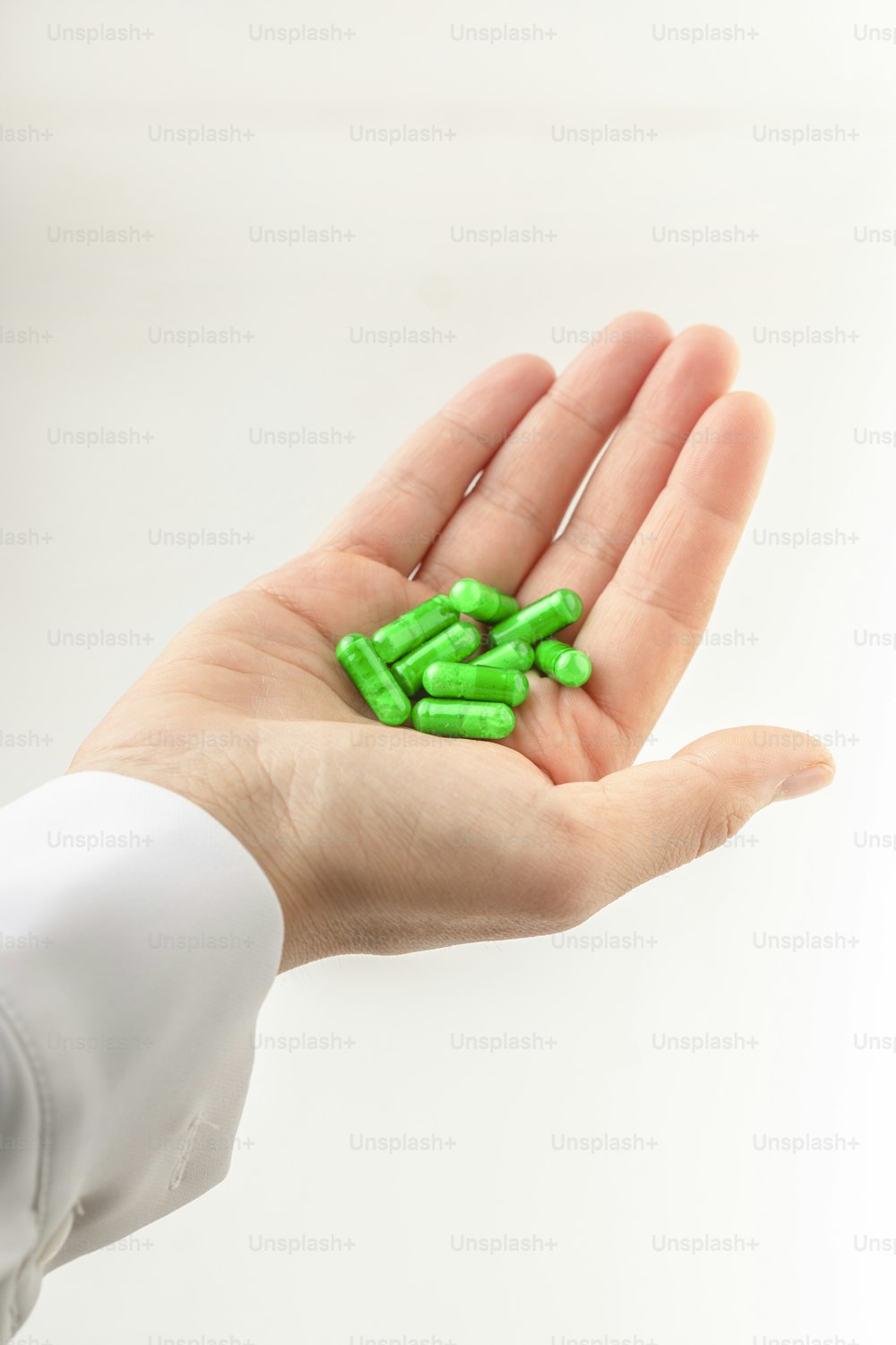 Eine Hand, die eine Handvoll grüner Pillen hält