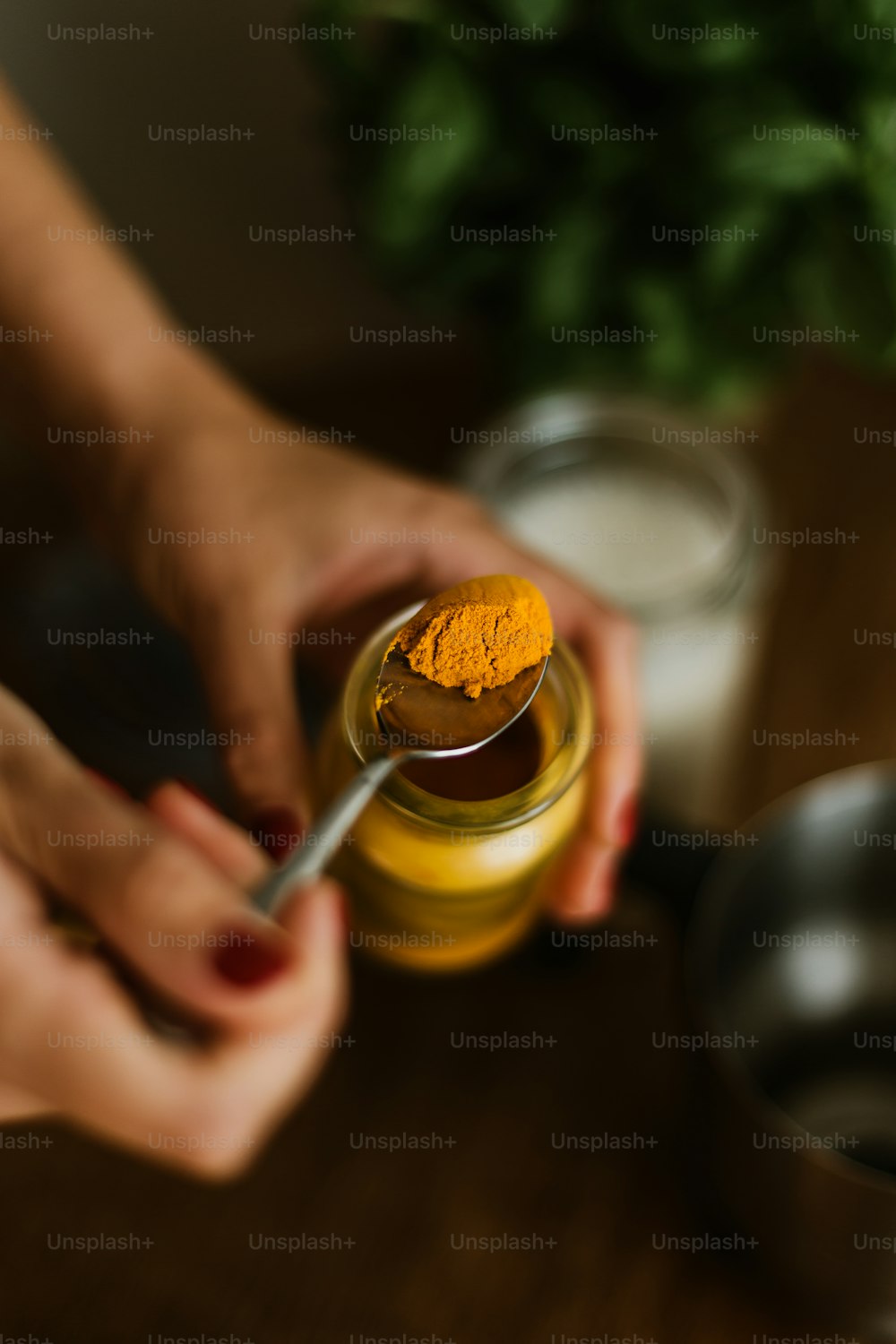 une personne tenant une cuillère au-dessus d’un pot de moutarde