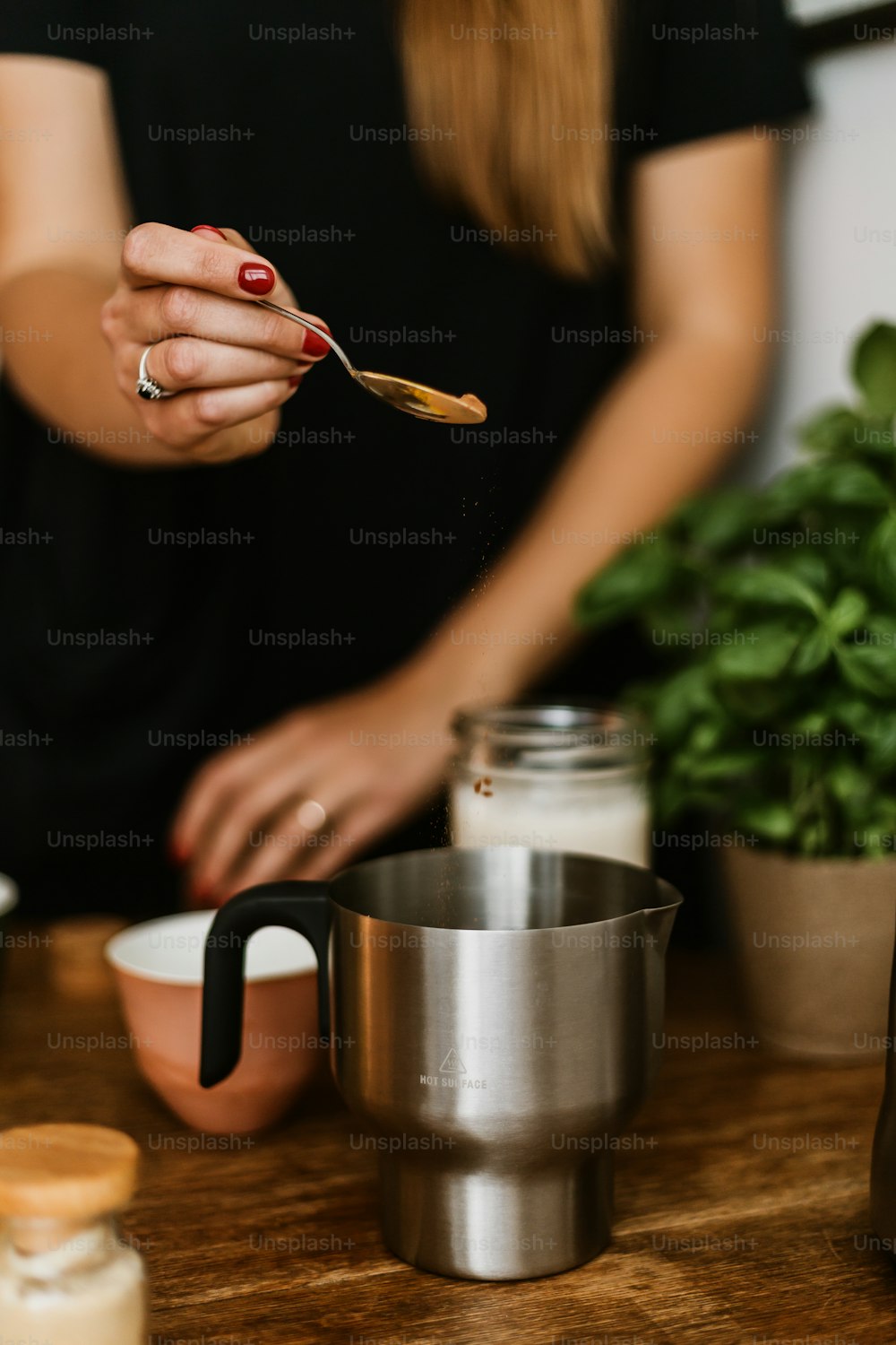 Une femme tenant une cuillère au-dessus d’une tasse sur une table