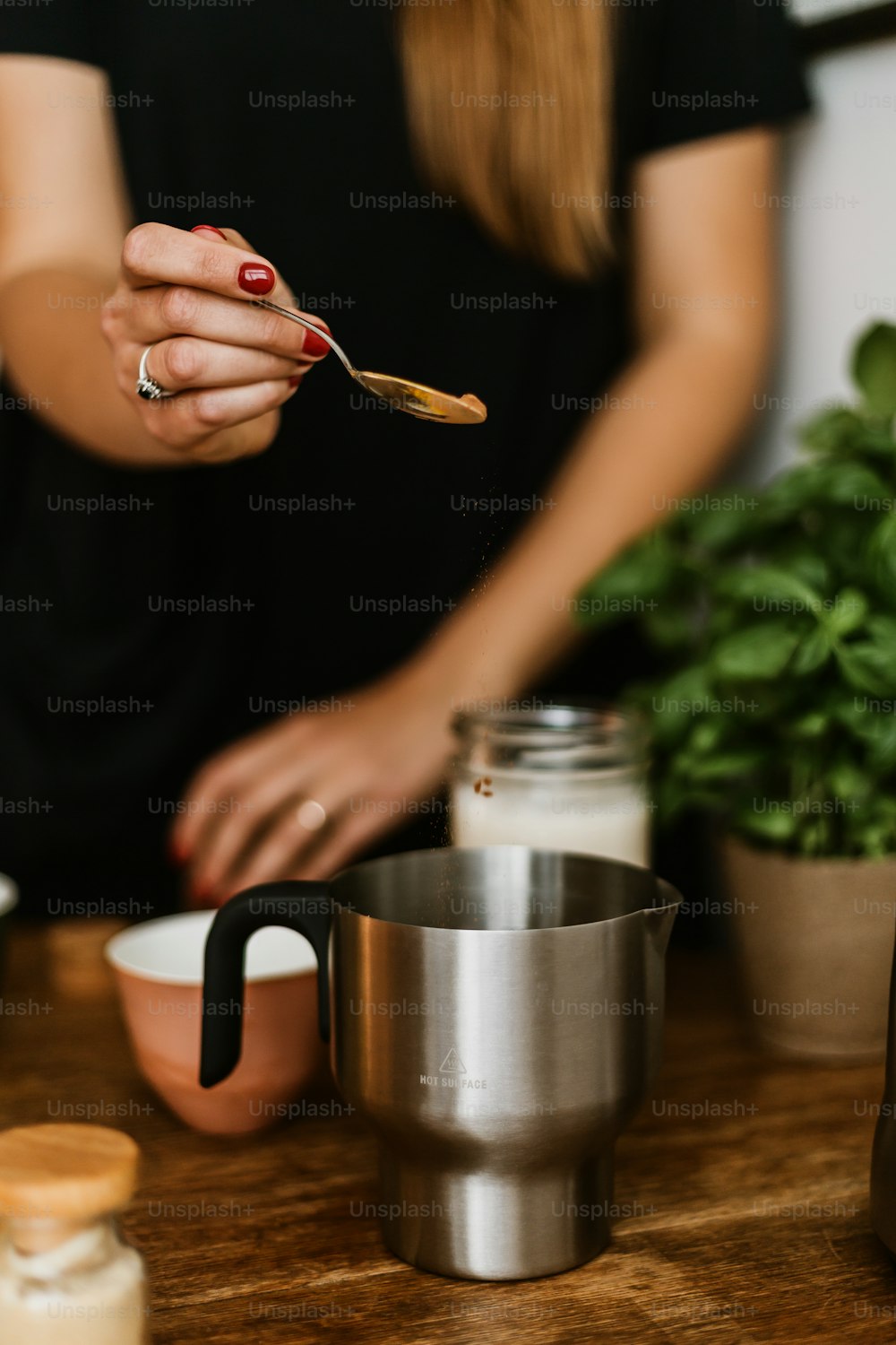a woman holding a spoon over a cup on a table