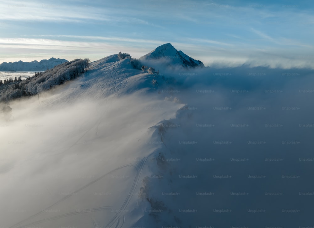 Una montagna coperta di neve e nuvole sotto un cielo blu