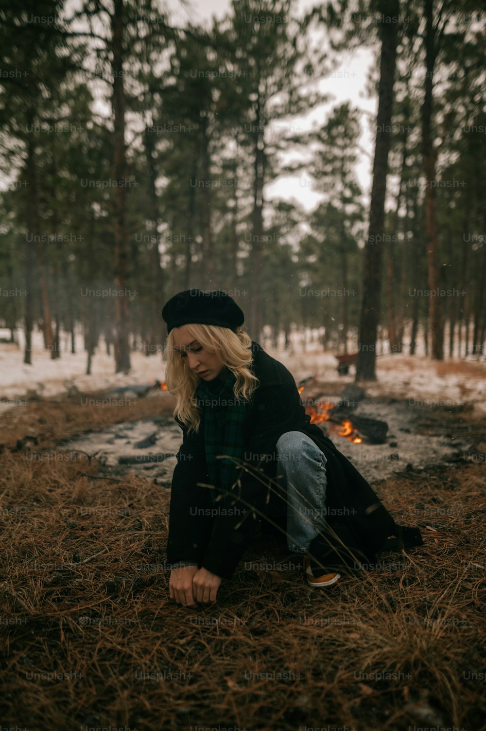 a woman sitting on the ground in the woods
