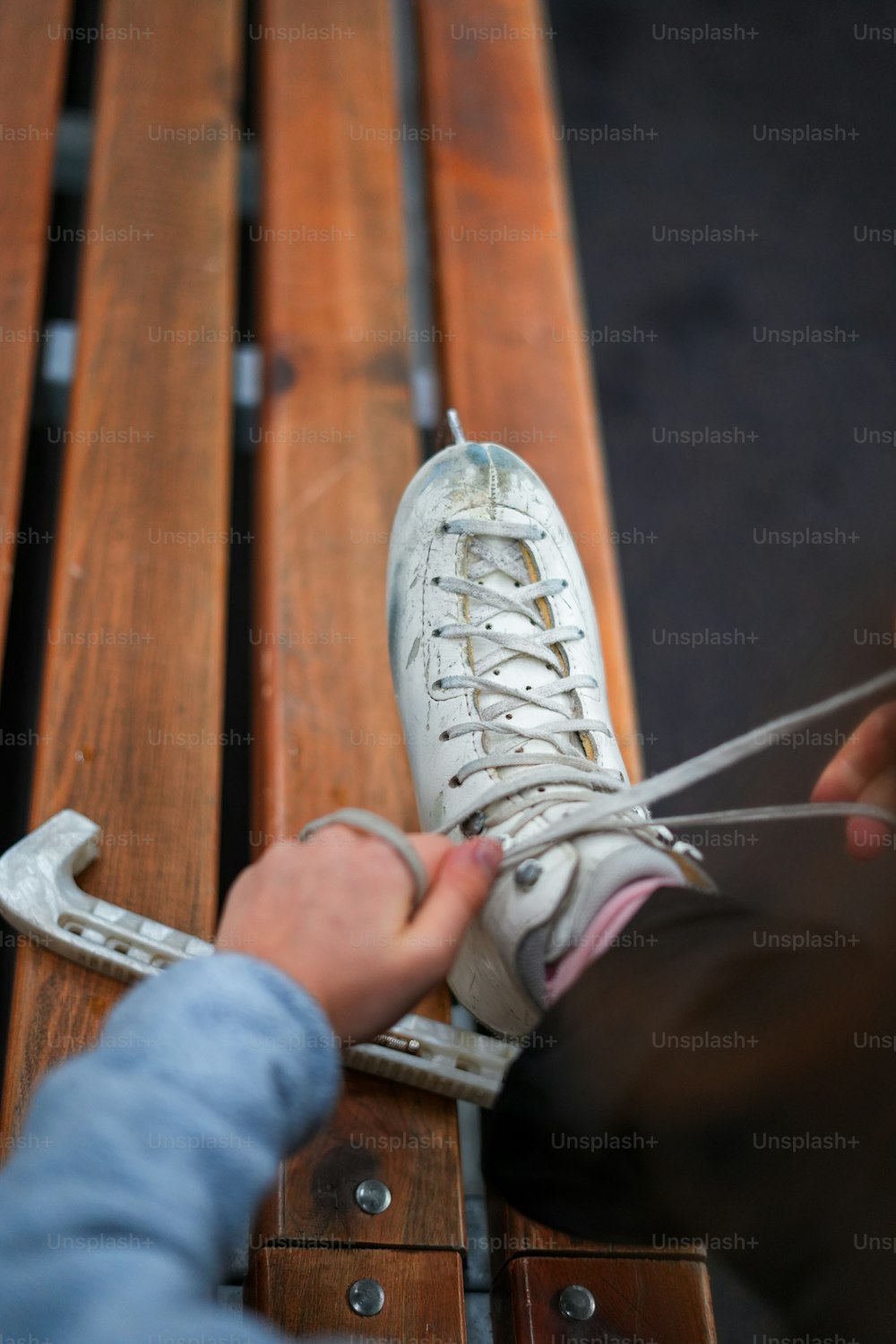 uma pessoa amarrando um par de tênis brancos em um banco