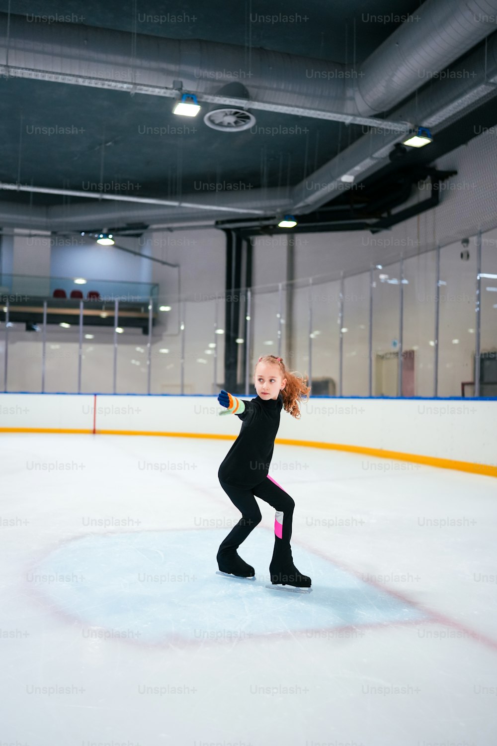 Ein junges Mädchen läuft auf einer Eisbahn Schlittschuh