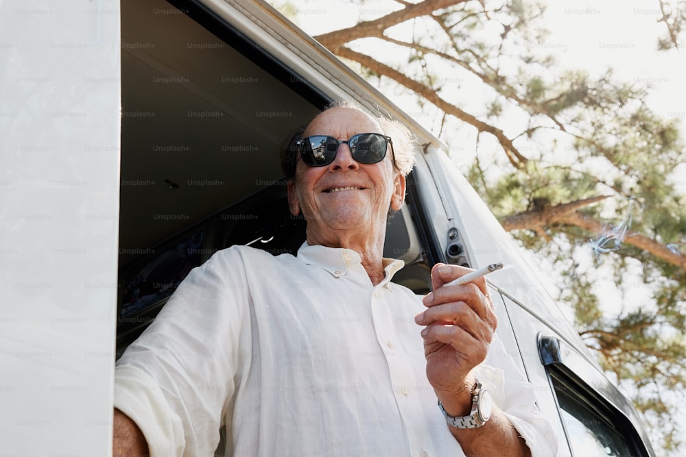 a man in sunglasses smoking a cigarette in front of a van