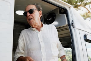 a man in a white shirt and sunglasses standing next to a white van
