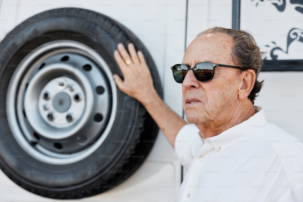a man in sunglasses touching a tire on a wall