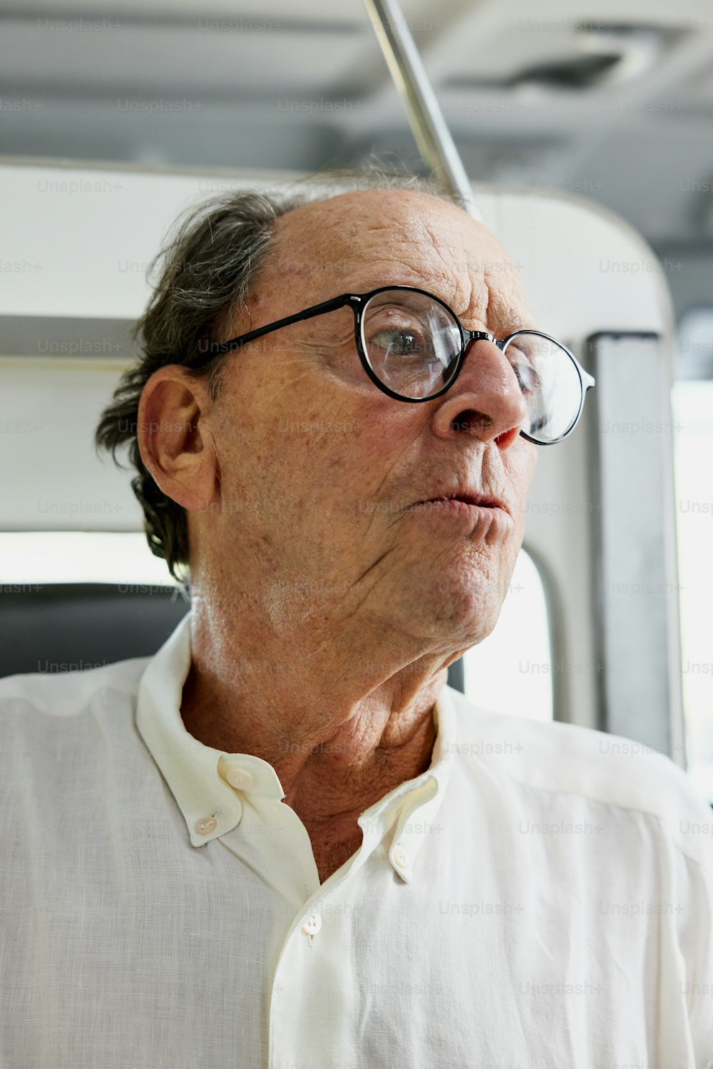 um homem mais velho usando óculos e uma camisa branca