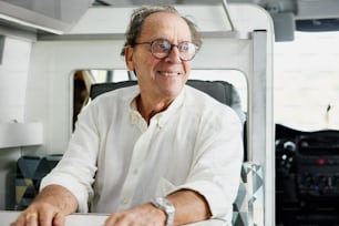 a man in a white shirt and glasses sitting at a table