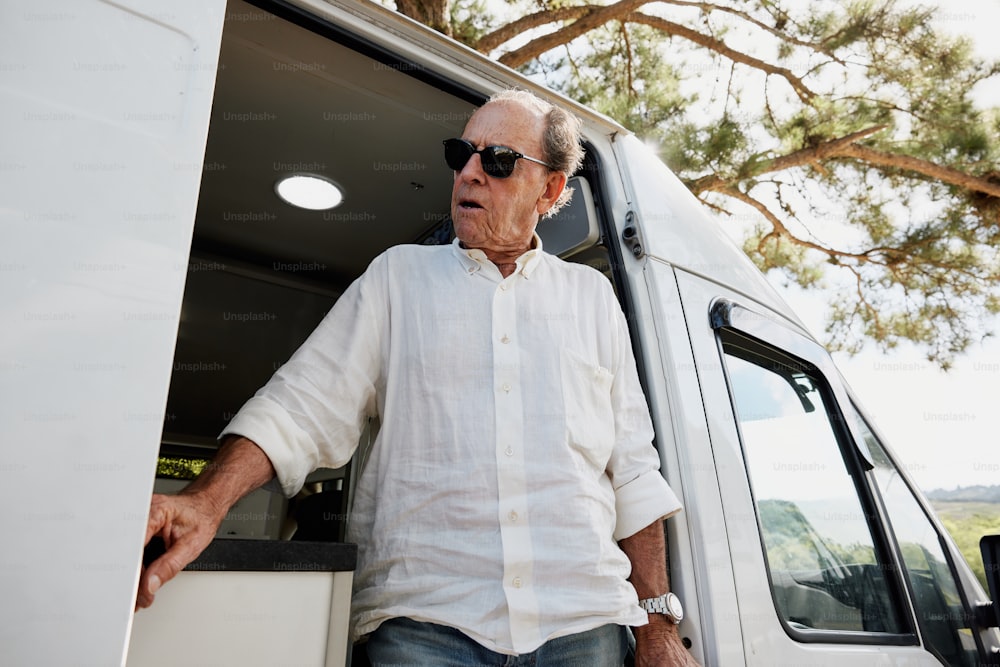 a man in a white shirt and sunglasses standing in the back of a truck