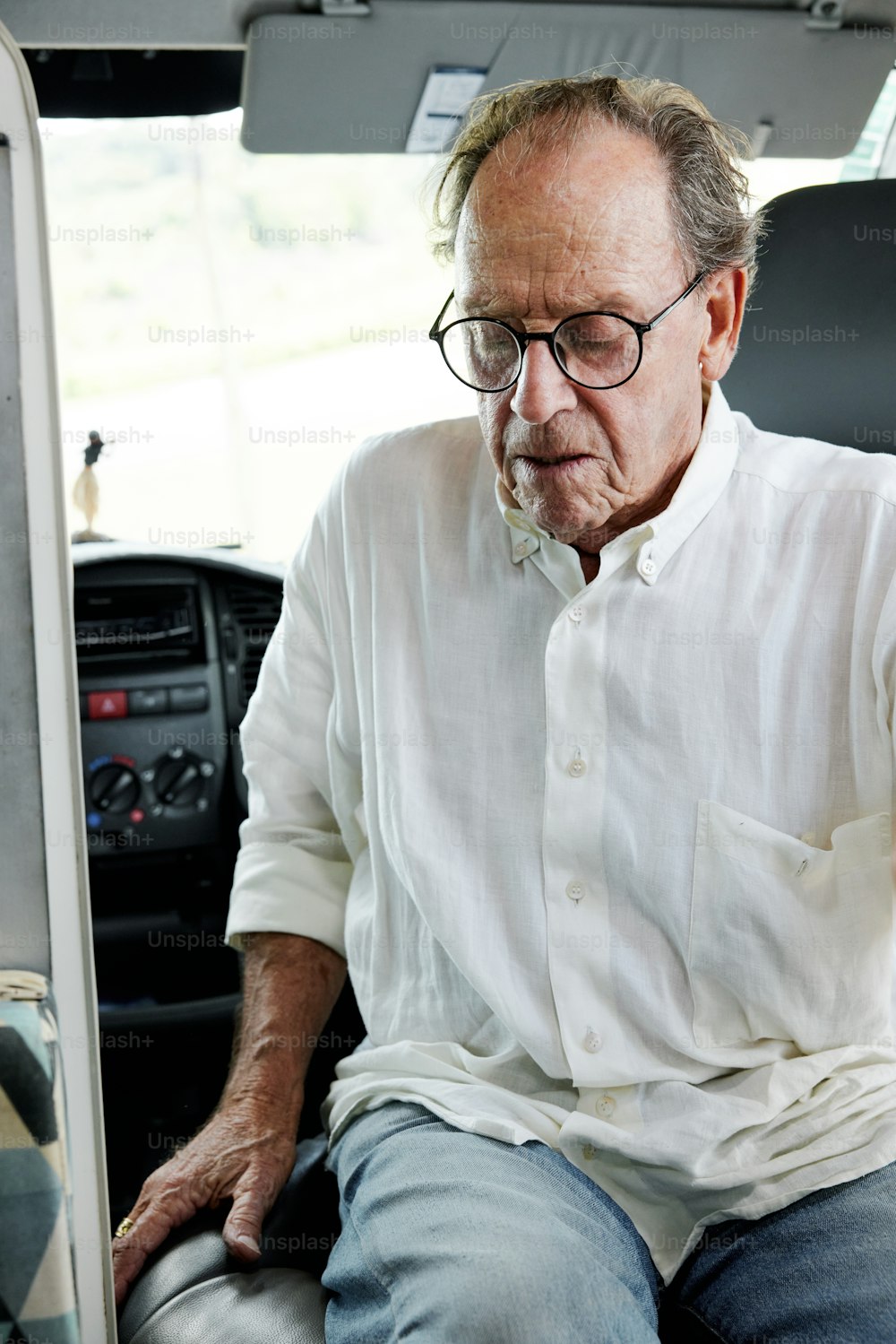a man in a white shirt and glasses sitting in a vehicle