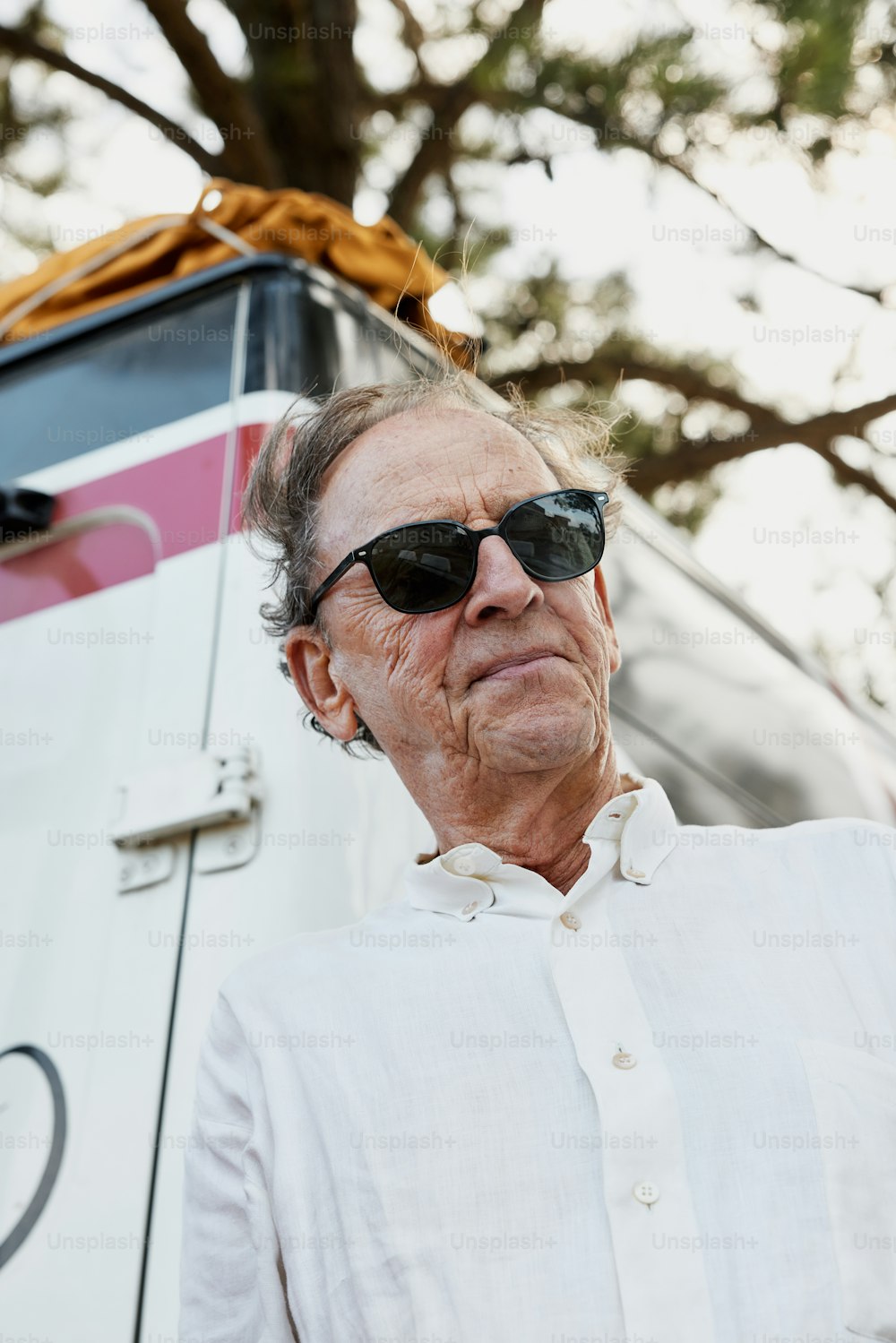 an old man wearing sunglasses standing in front of a bus
