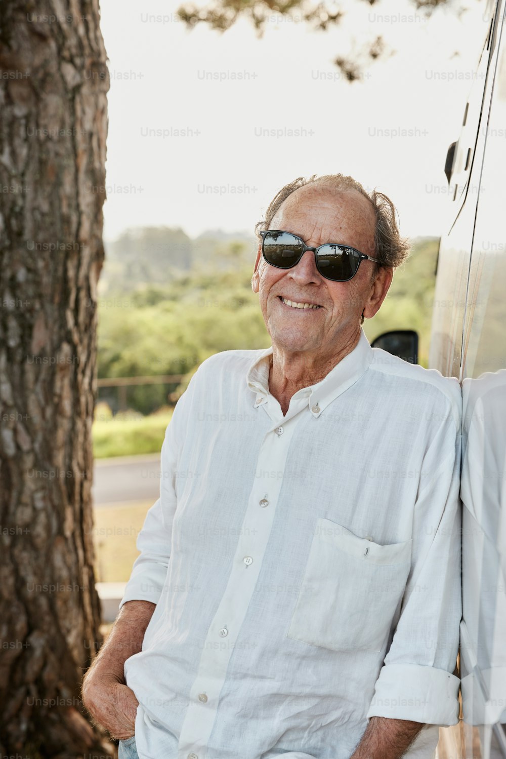 a man in sunglasses leaning against a tree