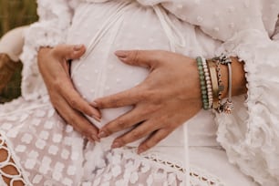 a pregnant woman wearing bracelets and a white dress