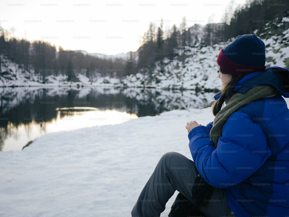 a woman in a blue jacket sitting in the snow