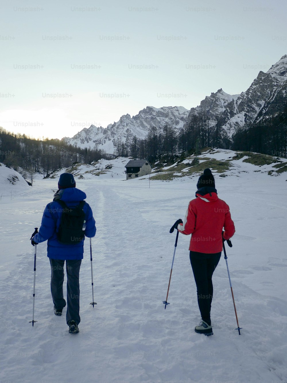 a couple of people riding skis across snow covered ground