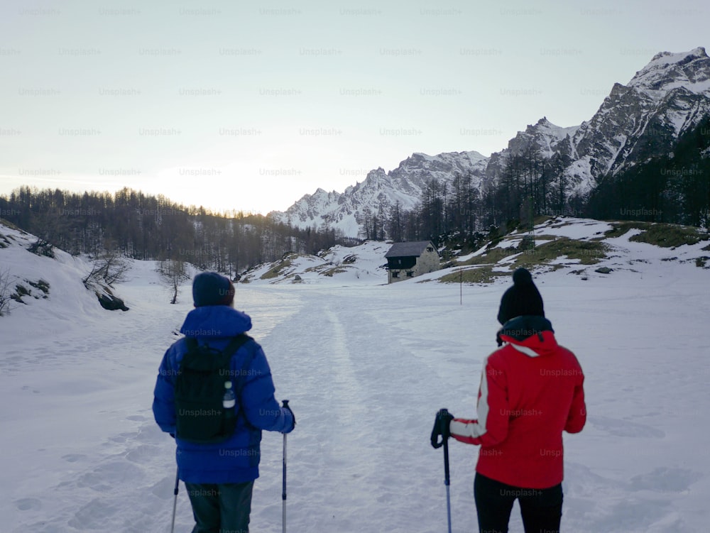 a couple of people riding skis across snow covered ground