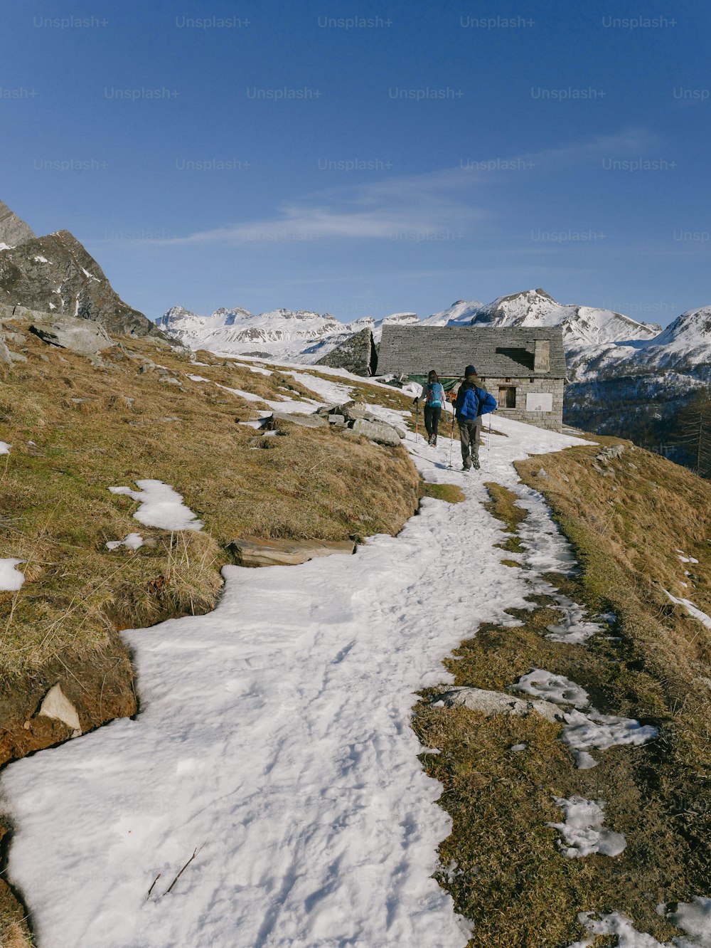 a couple of people walking up a snow covered hill