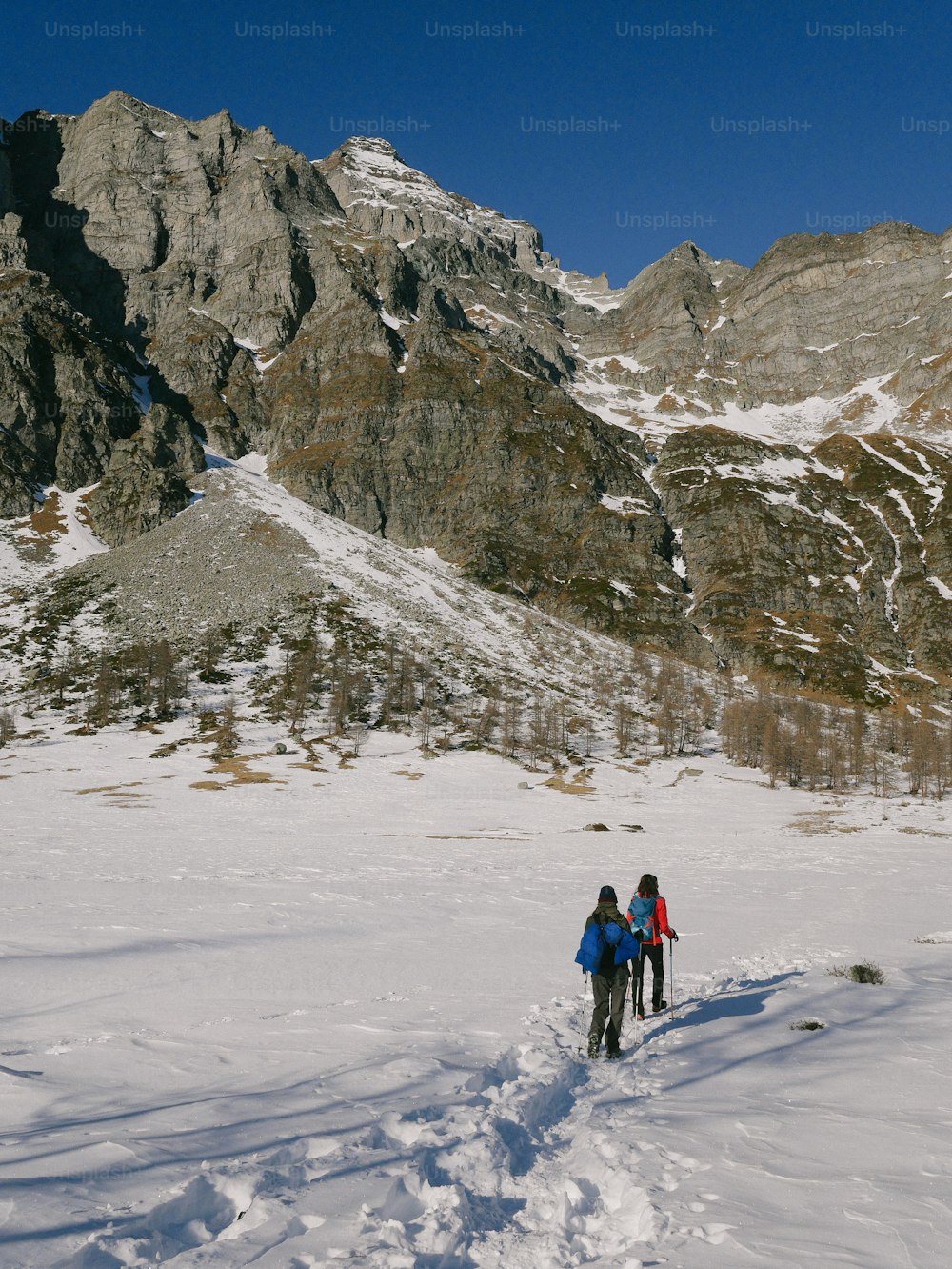 um par de pessoas andando de esqui através de uma encosta coberta de neve