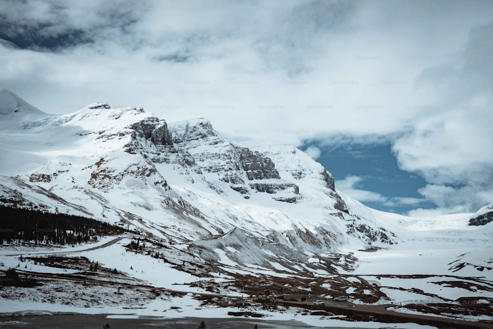 a mountain covered in snow under a cloudy sky