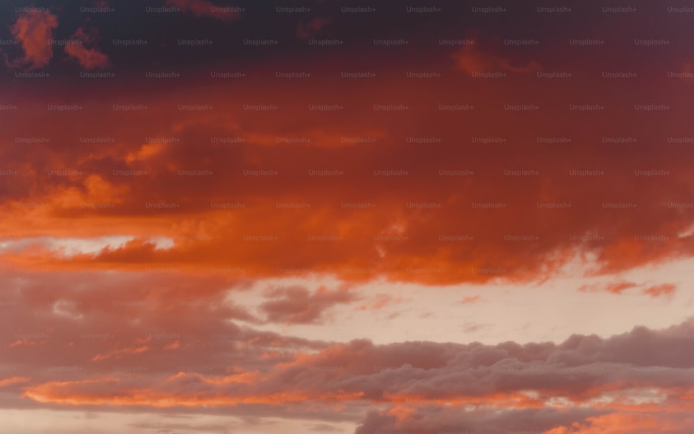 a plane flying through a cloudy sky at sunset