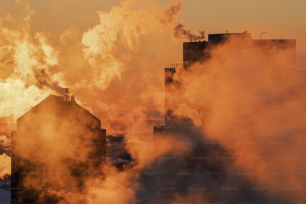 Il fumo si alza da un edificio industriale mentre il sole tramonta