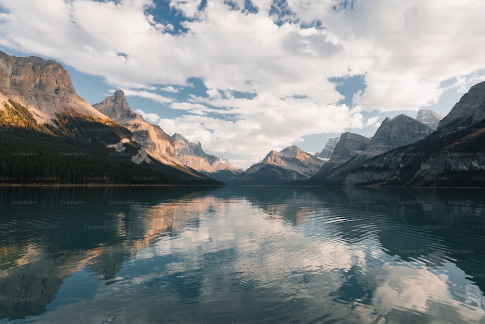 a body of water surrounded by mountains under a cloudy sky