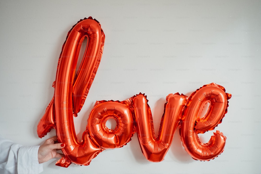 a person holding a red balloon in the shape of the word love