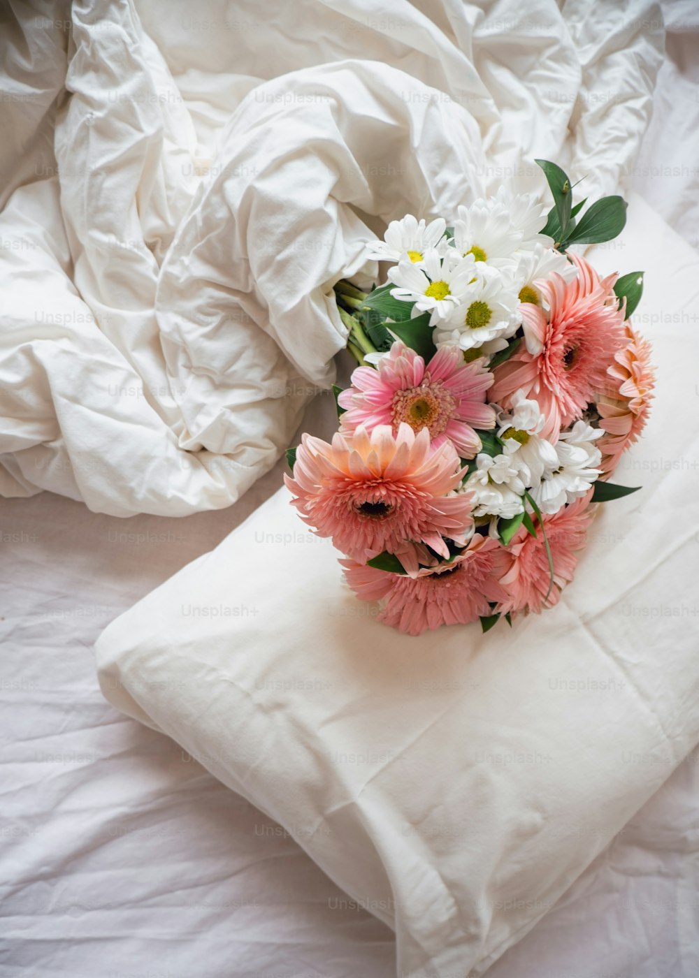 a bouquet of flowers on a pillow on a bed