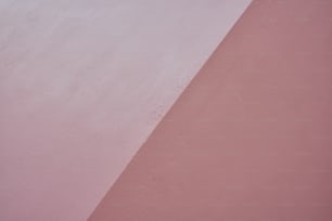 uma pessoa andando de skate em cima de uma parede rosa